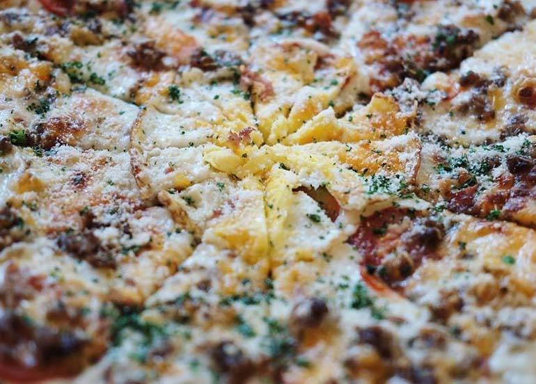 Vigan Pizza topped with cheese, vigan longganisa, and herbs